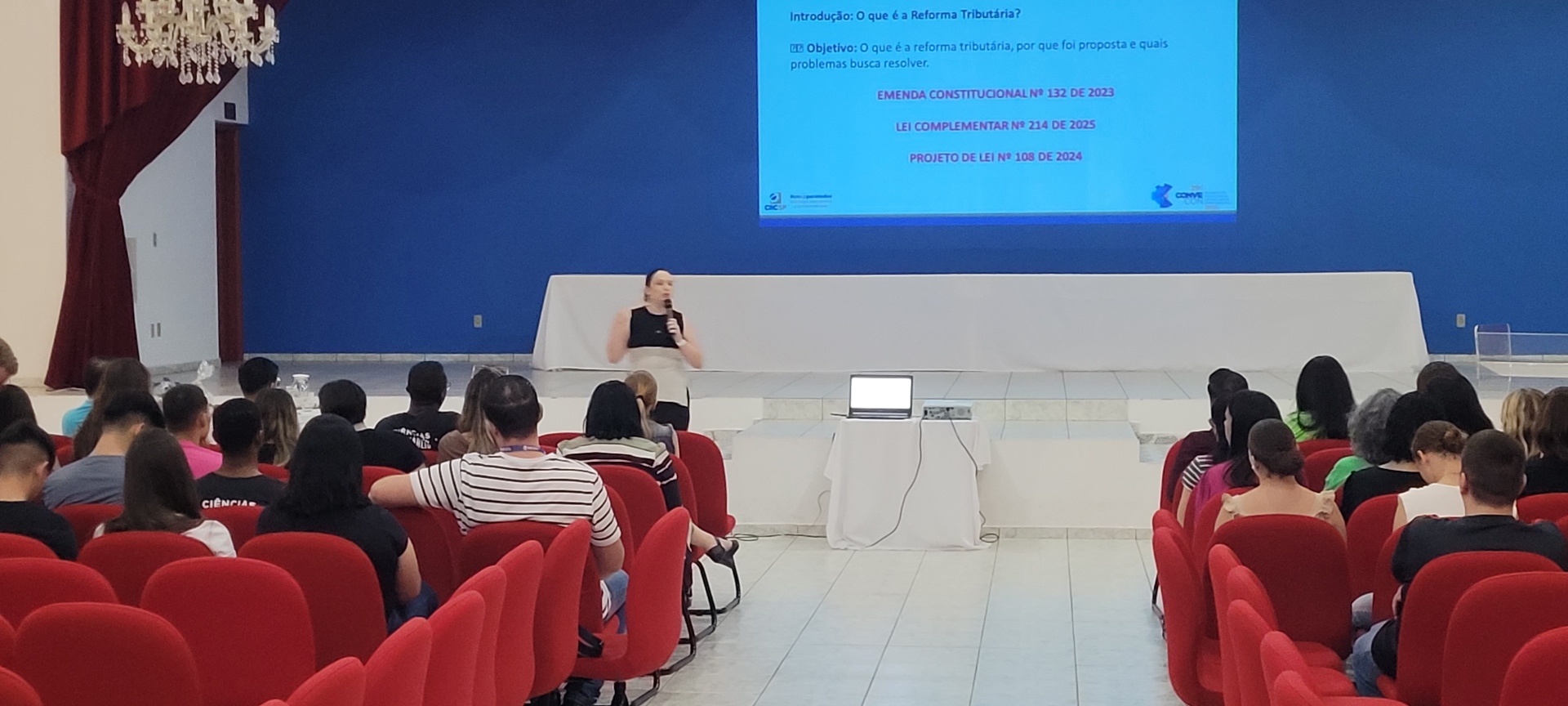 Plateia no auditório universitário — Desafios da Reforma Tributária · CONVECON mar 2025